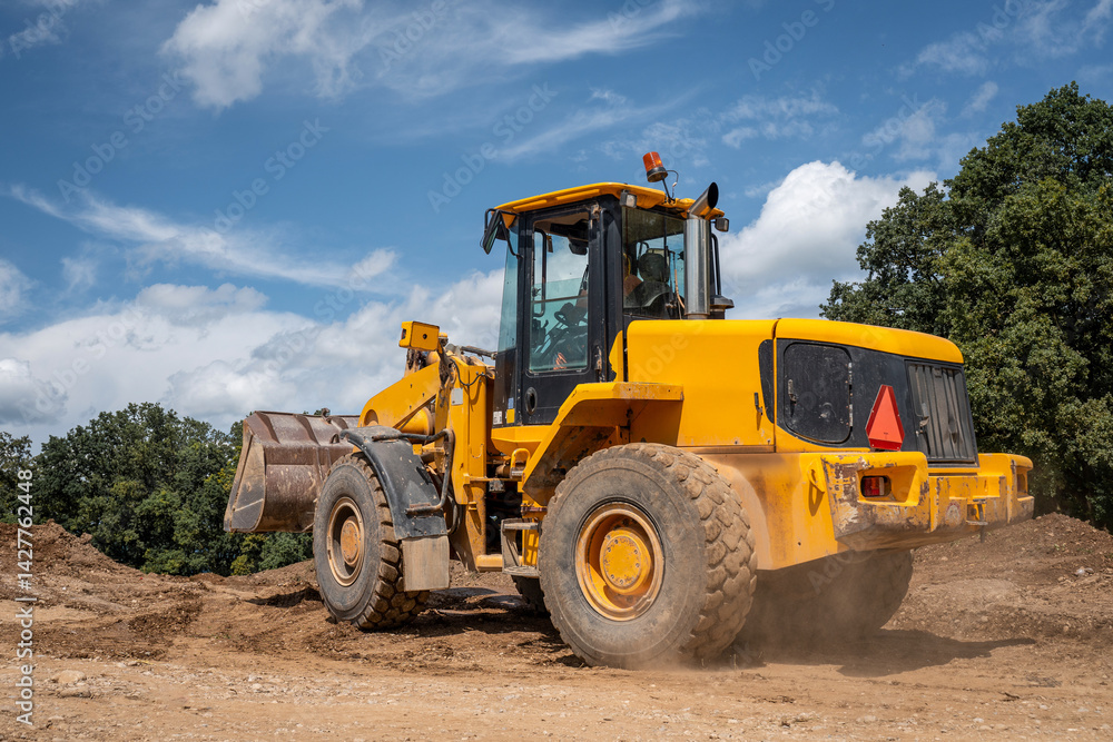 Wheeled loader moving construction materials like gravel and earth on highway construction site Wheeled loader moving construction materials like gravel and earth on highway construction site