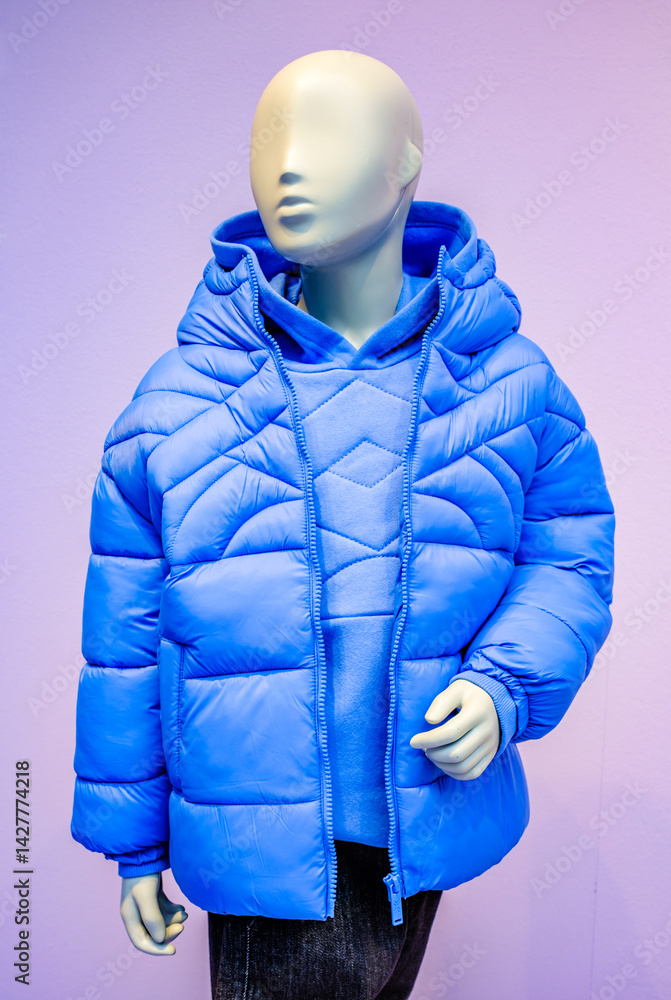 Shop display showcases a blue padded jacket worn by a mannequin in a clothing store located in Austria, highlighting modern fashion trends in winter apparel