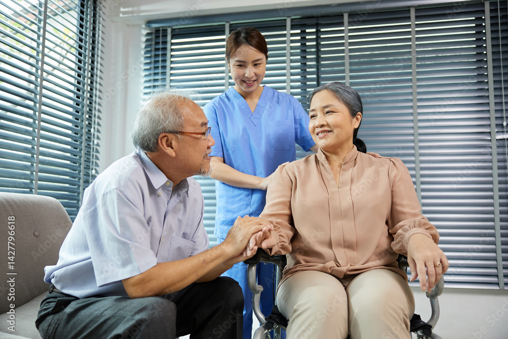 nurse or caregiver helping senior woman sitting on wheelchair and senior man support her at home