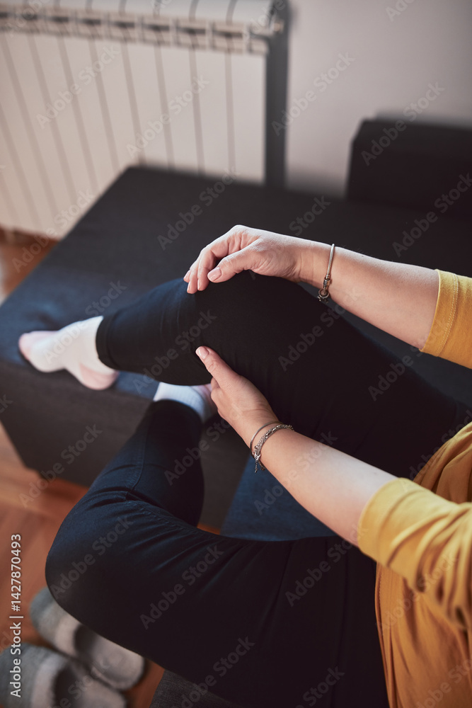 Woman with painful knee and leg injury at home.