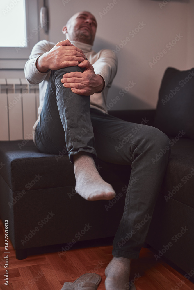 Man with painful knee and leg injury at home.