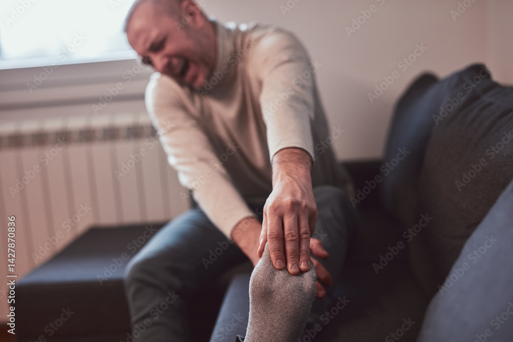 Man with ankle and foot pain at home.