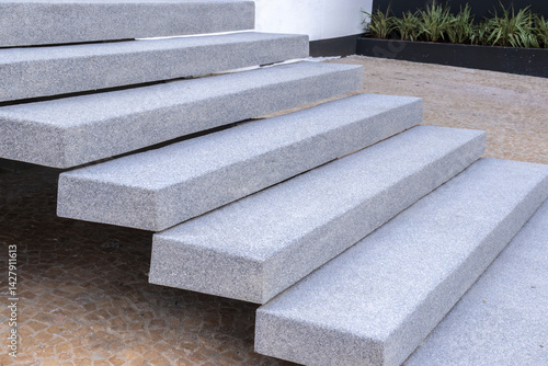 Obraz na płótnie Close-up of modern granite staircase in an outdoor setting, juxtaposed with green vegetation. This image conveys contemporary architectural design, highlighting the durability and texture of the stone w salonie