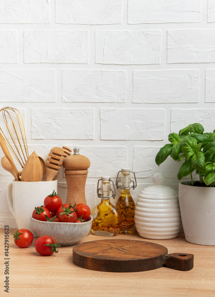 Kitchen countertop with cutting board, tomatoes, spices, and basil plant