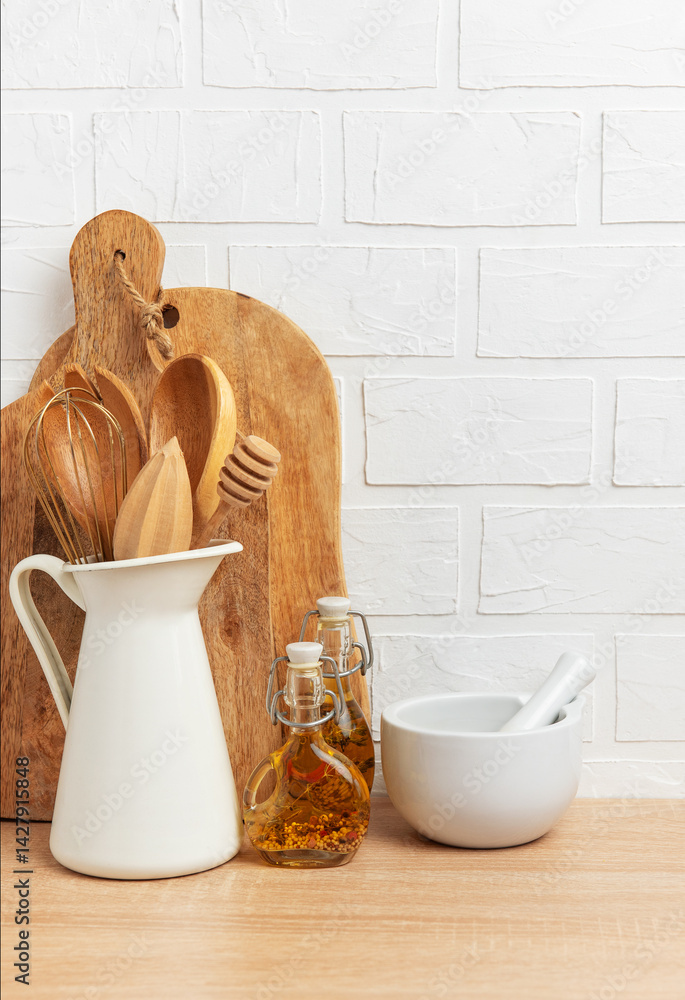 Kitchen utensils resting on wooden countertop with white brick wall background