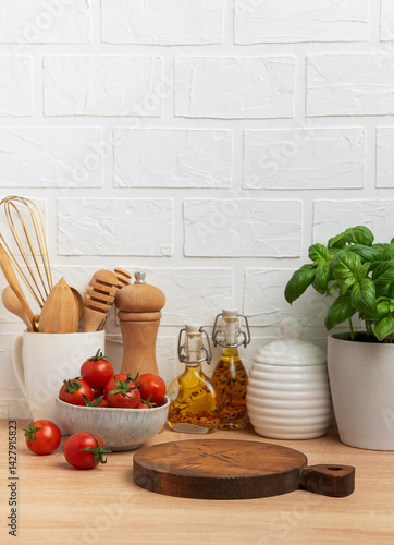 Obraz na płótnie Kitchen countertop with cutting board, tomatoes, spices, and basil plant w salonie