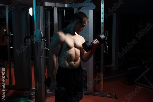 Obraz na płótnie sport bodybuilding, training and people concept - close up of young man with dumbbell flexing biceps over dark gym background w salonie
