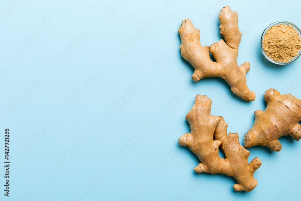 Fototapeta premium Finely dry Ginger powder in bowl with green leaves isolated on colored background. top view flat lay