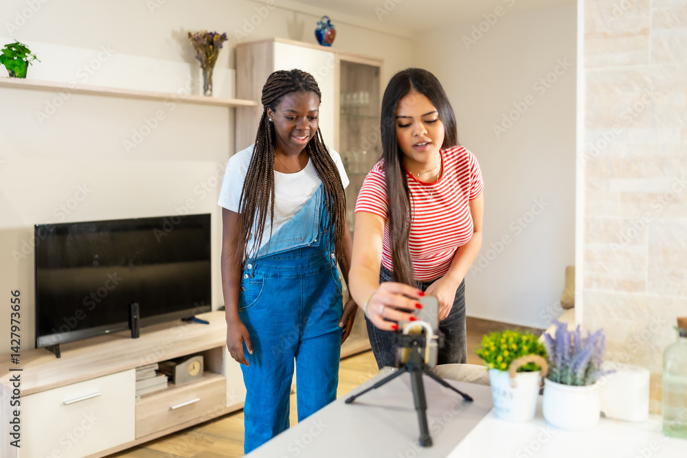 Teenage girls recording video content with smartphone and microphone at home