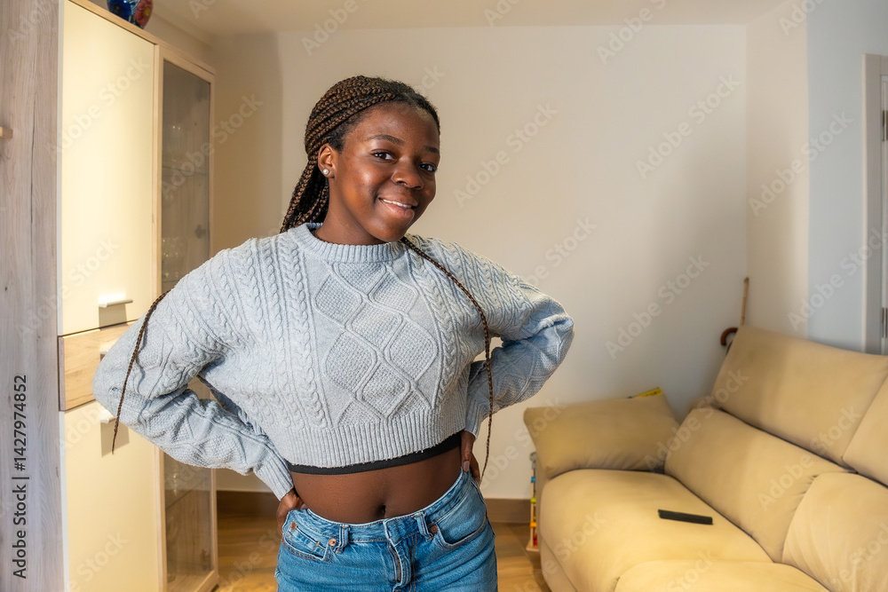 Smiling teenager posing with hands on hips in living room