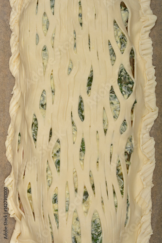 Obraz na płótnie A close-up shows a lattice-topped savory pie filled with a creamy spinach mixture, ready for baking w salonie