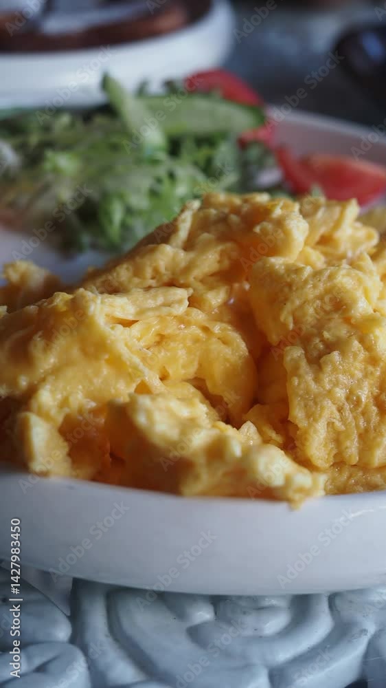 Fluffy scrambled eggs served with fresh salad and tomatoes Fluffy scrambled eggs served with fresh salad and tomatoes