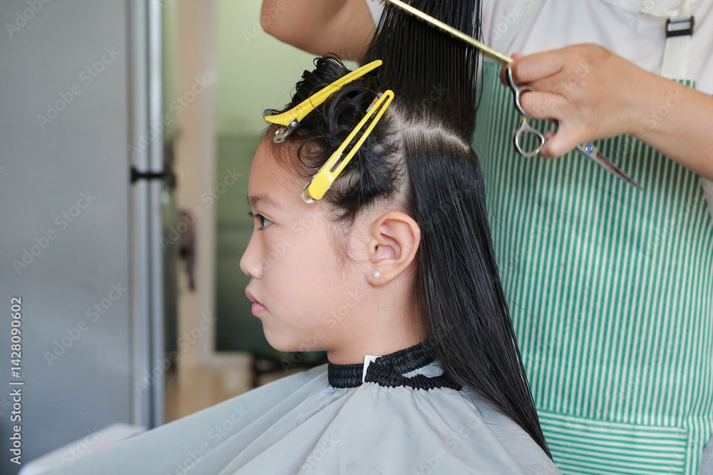 Portrait of Asian girl child getting her haircut in a beauty salon. Close up.