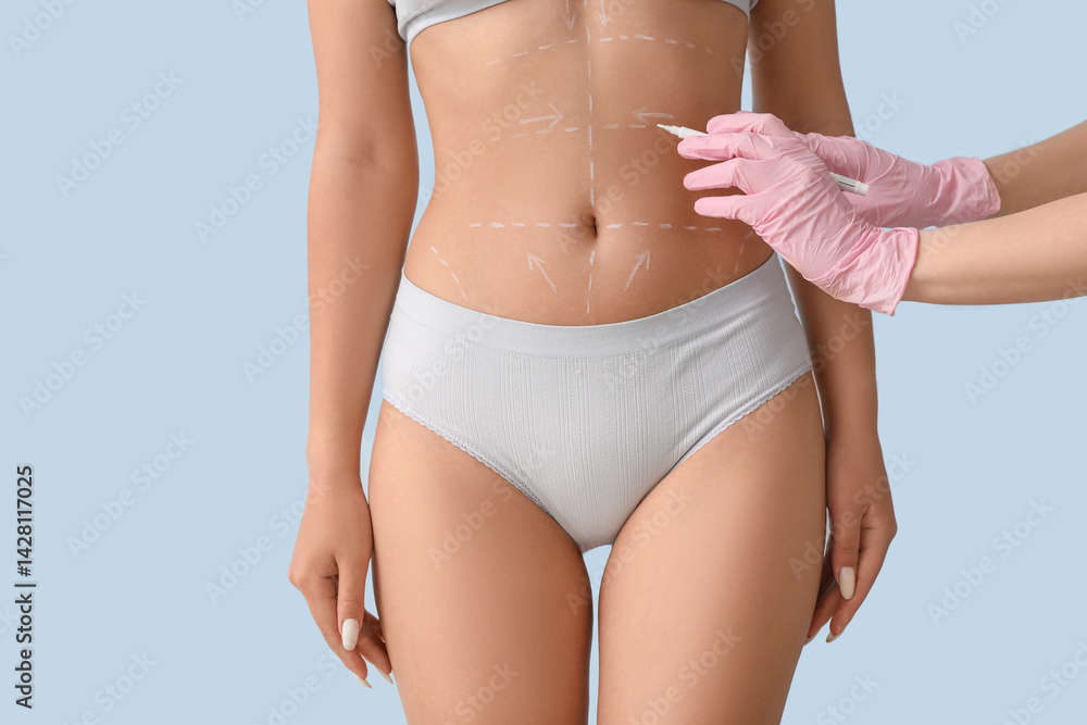 Plastic surgeon marking woman's belly on light background, closeup