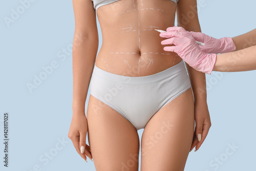 Obraz na płótnie Plastic surgeon marking woman's belly on light background, closeup w salonie