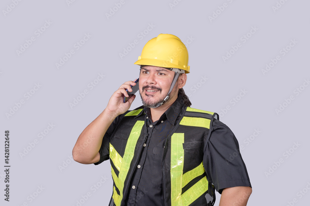 Construction worker in safety vest and helmet talks on mobile phone, coordinating project details or receiving updates on jobsite issues. Construction worker in safety vest and helmet talks on mobile phone, coordinating project details or receiving updates on jobsite issues.