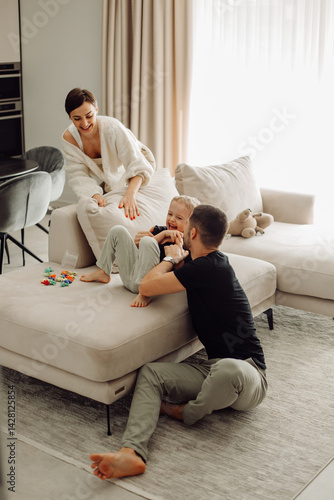 Happy family tickling and playing together on sofa in living room