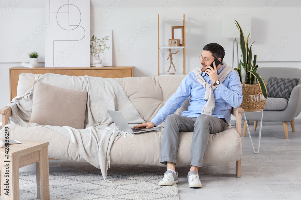 © Pixel-Shot - Young male teacher with laptop and mobile phone giving online lesson at home