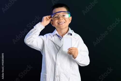 Cute little boy in lab coat with protective glasses and blank name tag on bla...
