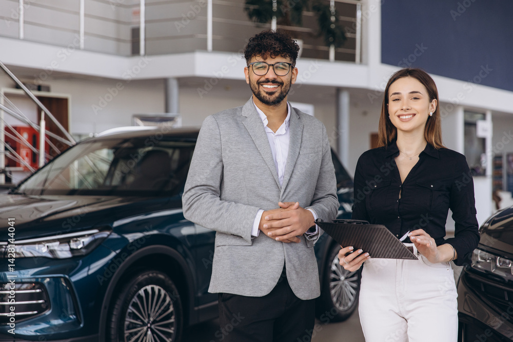 Car salesman and saleswoman standing in car dealership showroom Car salesman and saleswoman standing in car dealership showroom