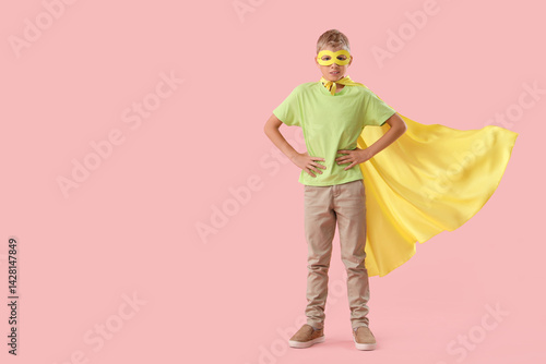 Teenage boy dressed as superhero on pink background
