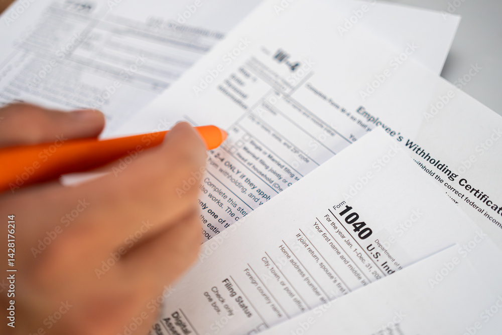 Fototapeta premium Male freelancer hand holds pen preparing for filling necessary tax forms to report annual income to comply with federal and state tax laws avoiding penalties