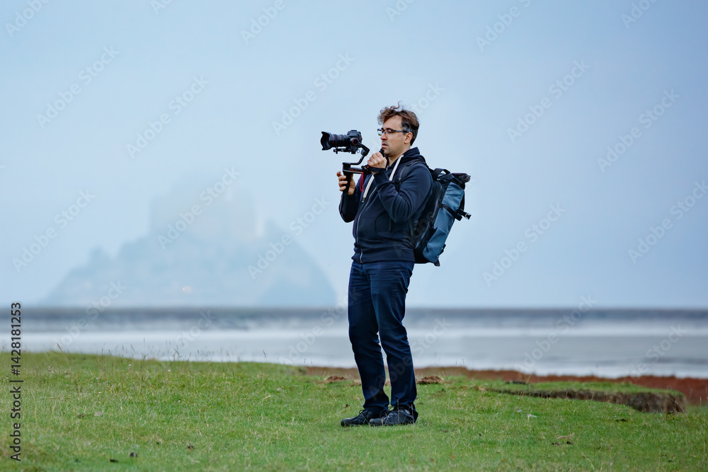 Man equipped with a camera films hazy Mont Saint Michel castle