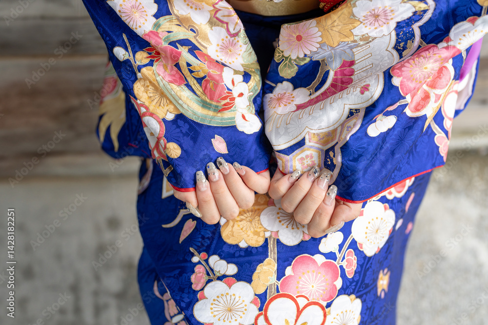 A local city in Japan on a rainy summer day. A Japanese woman wearing a blue teenage kimono in a traditional garden. She shows her nails.