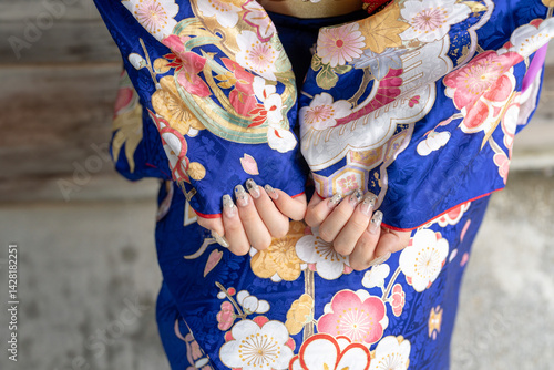Obraz na płótnie A local city in Japan on a rainy summer day. A Japanese woman wearing a blue teenage kimono in a traditional garden. She shows her nails. w salonie