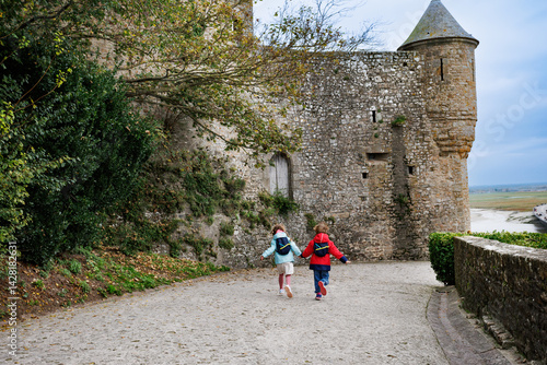 Obraz na płótnie Kids in jackets run happily historic path of Mont Saint Michel w salonie
