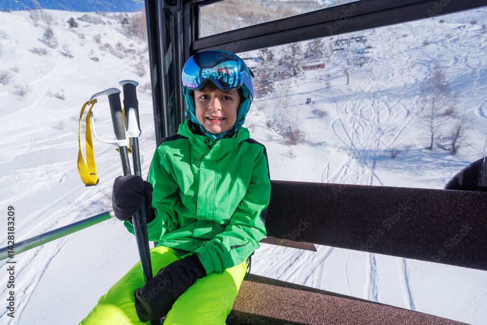 Happy teenage boy in ski gear takes scenic ride up snowy slopes