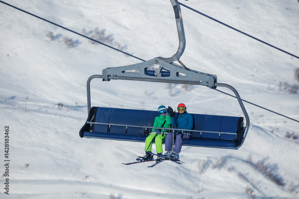 Skiers teen and adult enjoy scenic chairlift ride over slopes