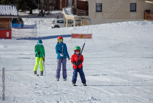 Ski school ascend on tow lift a snowy mountain in bright gear
