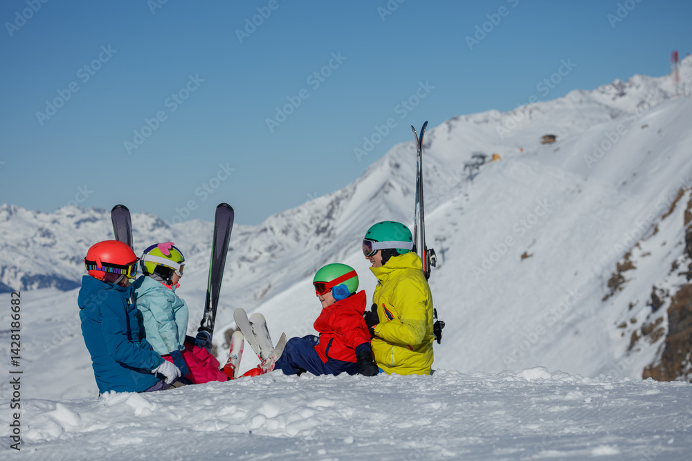 Skiing family rests on snow, savoring breathtaking mountain view