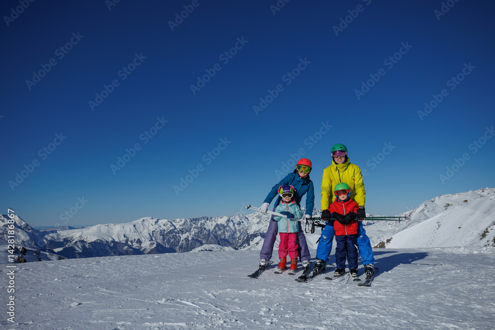 On a wintery slope, family of four stand ready to have fun ride