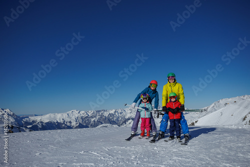 Obraz na płótnie On a wintery slope, family of four stand ready to have fun ride w salonie