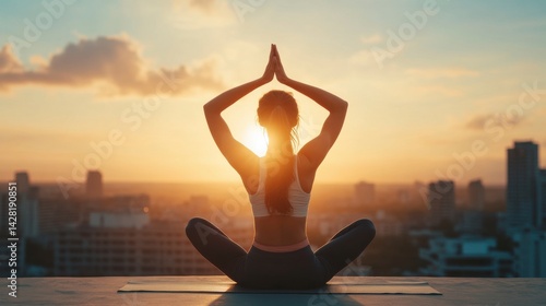 Silhouetted Woman Meditating at Sunset Over City Skyline