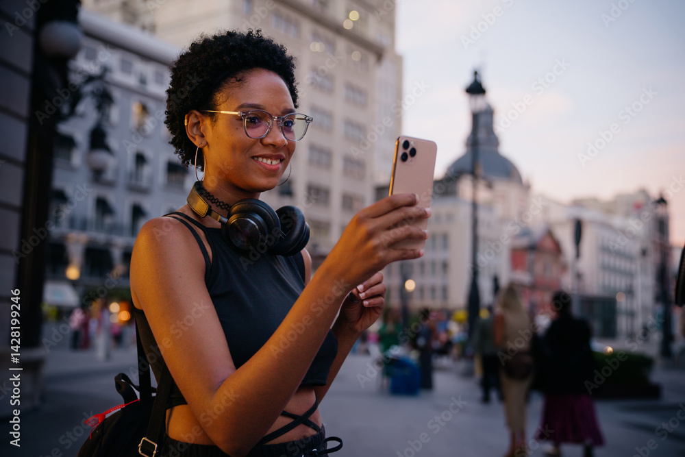 Stylish female traveler making a video call while sightseeing in a historic urban area, enjoying street atmosphere, possibly sharing travel tips or live streaming
