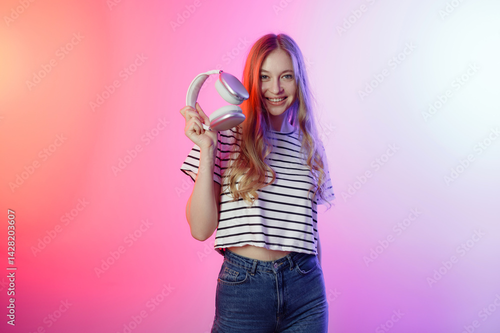 Young woman holding headphones in a colorful background, showcasing a vibrant lifestyle and love for music