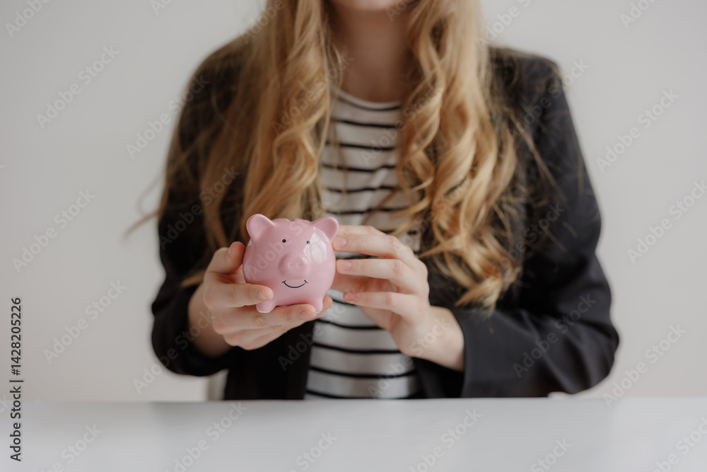 Business professional holding a pink piggy bank while discussing financial plans in a modern office setting