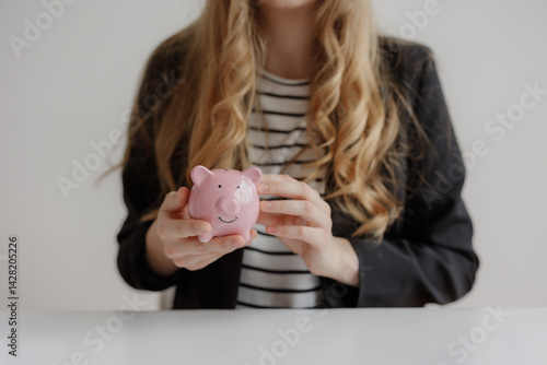 Obraz na płótnie Business professional holding a pink piggy bank while discussing financial plans in a modern office setting w salonie