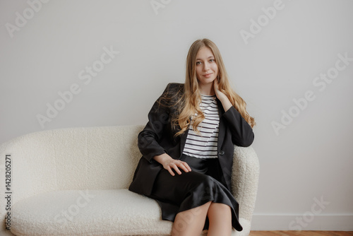 Obraz na płótnie Young professional woman sitting thoughtfully on a cozy couch in a minimalist room during daytime w salonie