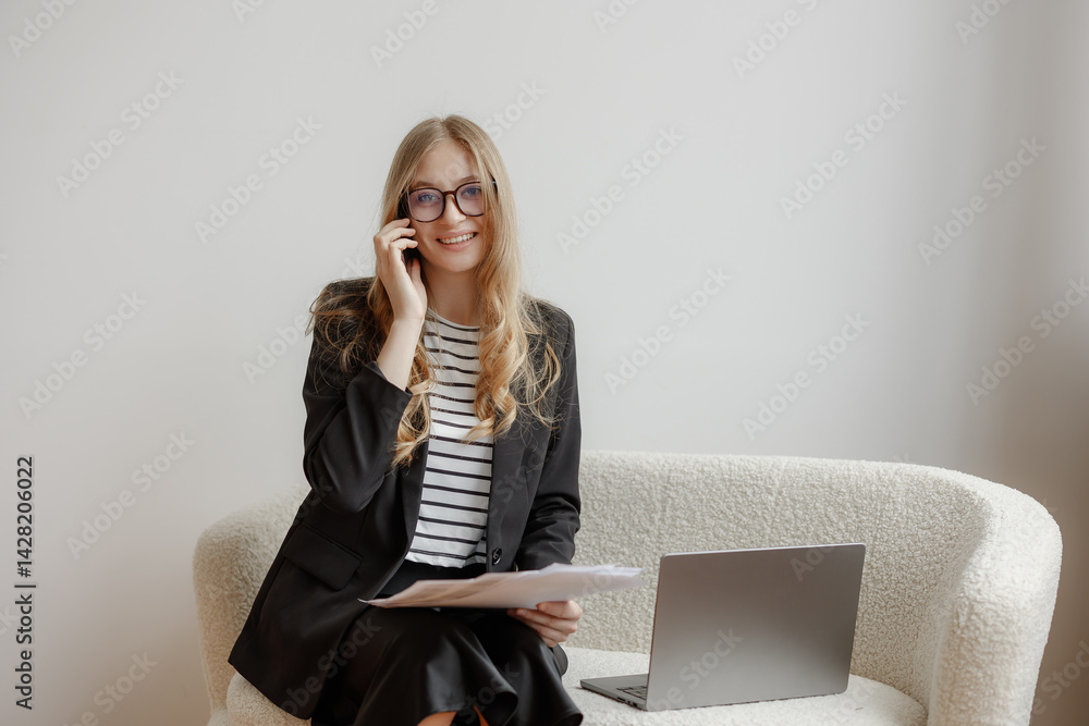 Businesswoman engages in a phone conversation while sitting on a couch in a modern office setting