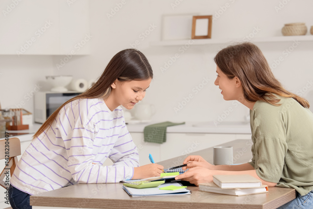 Teenage girl studying Math with tutor at table in kitchen Teenage girl studying Math with tutor at table in kitchen