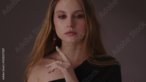 Beautiful girl with gold jewelry and loose hair in black clothes posing on a dark background. Beauty face and hair. Video 4k