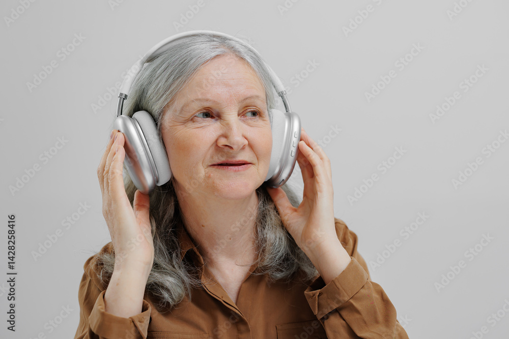Older woman enjoying music while wearing headphones in a serene indoor setting