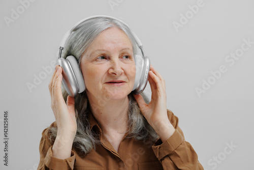 Obraz na płótnie Older woman enjoying music while wearing headphones in a serene indoor setting w salonie
