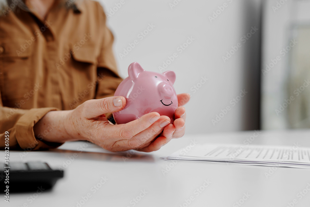 Holding a pink piggy bank at a desk while reviewing financial documents during a planning session