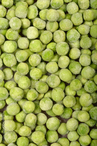 Obraz na płótnie A close-up, top-down shot shows a dense layer of frozen green peas, some with visible ice crystals w salonie