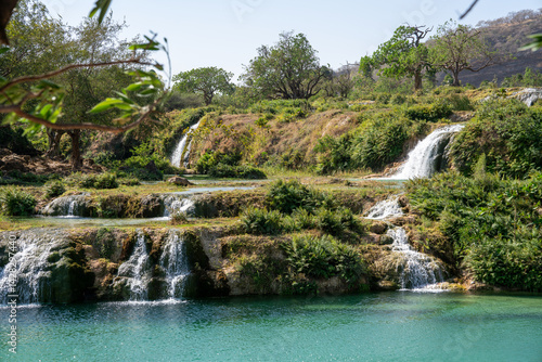 Kaskadenartige Wasserfälle in üppiger grüner Landschaft wadi darbat oman